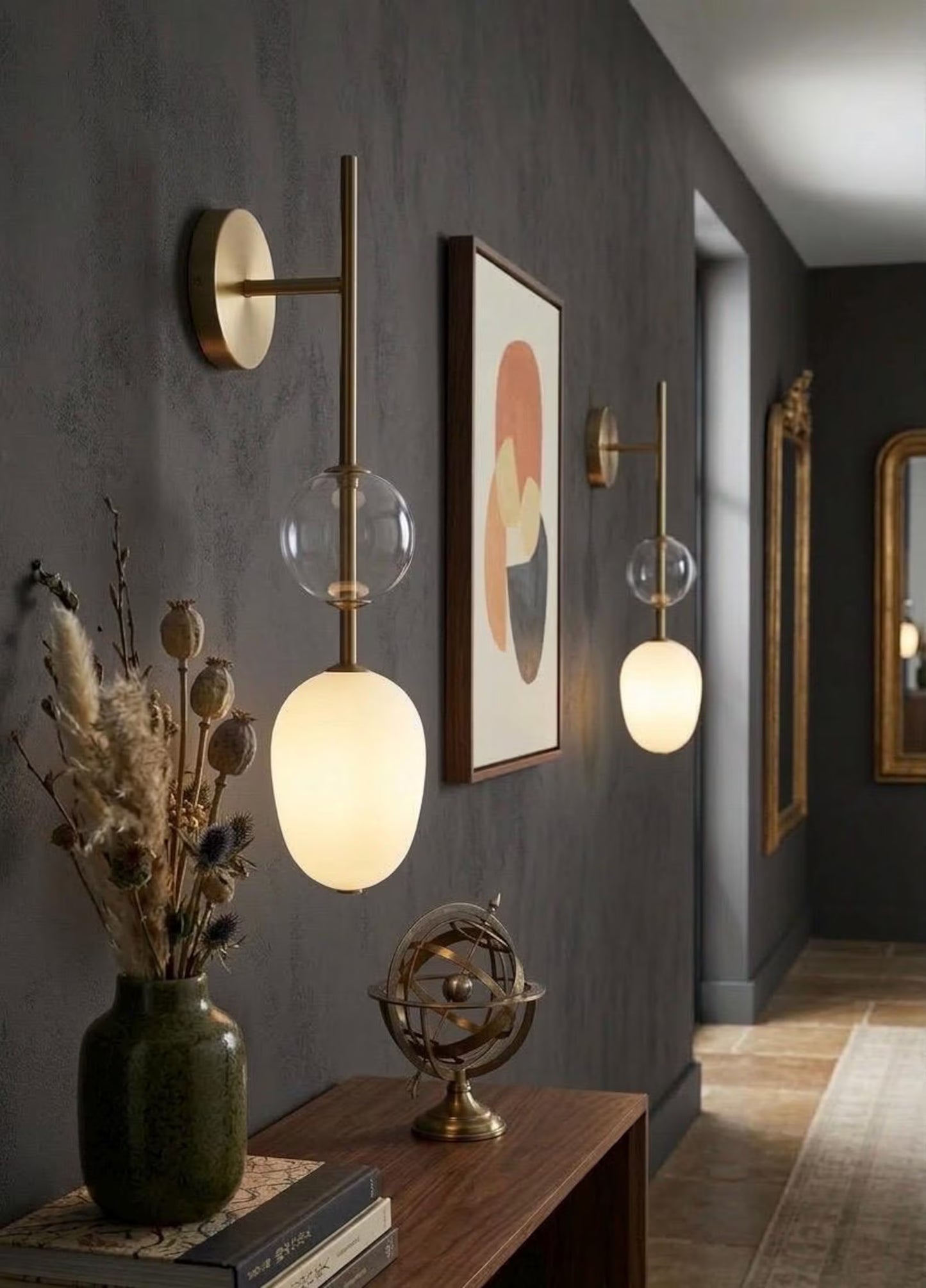 Modern interior design with wall lights, a vase with dried plants, and a framed abstract painting.