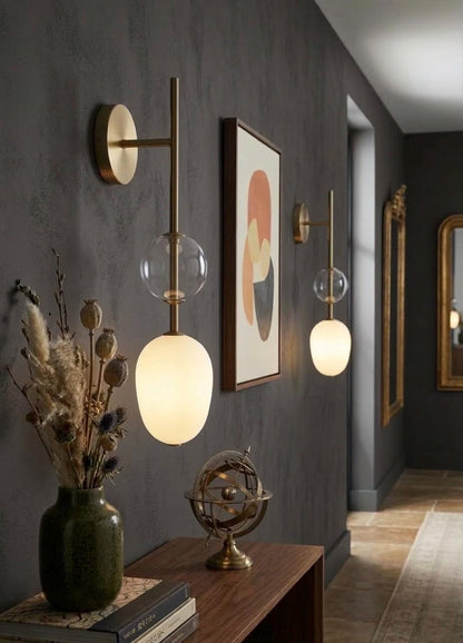 Modern interior design with wall lights, a vase with dried plants, and a framed abstract painting.