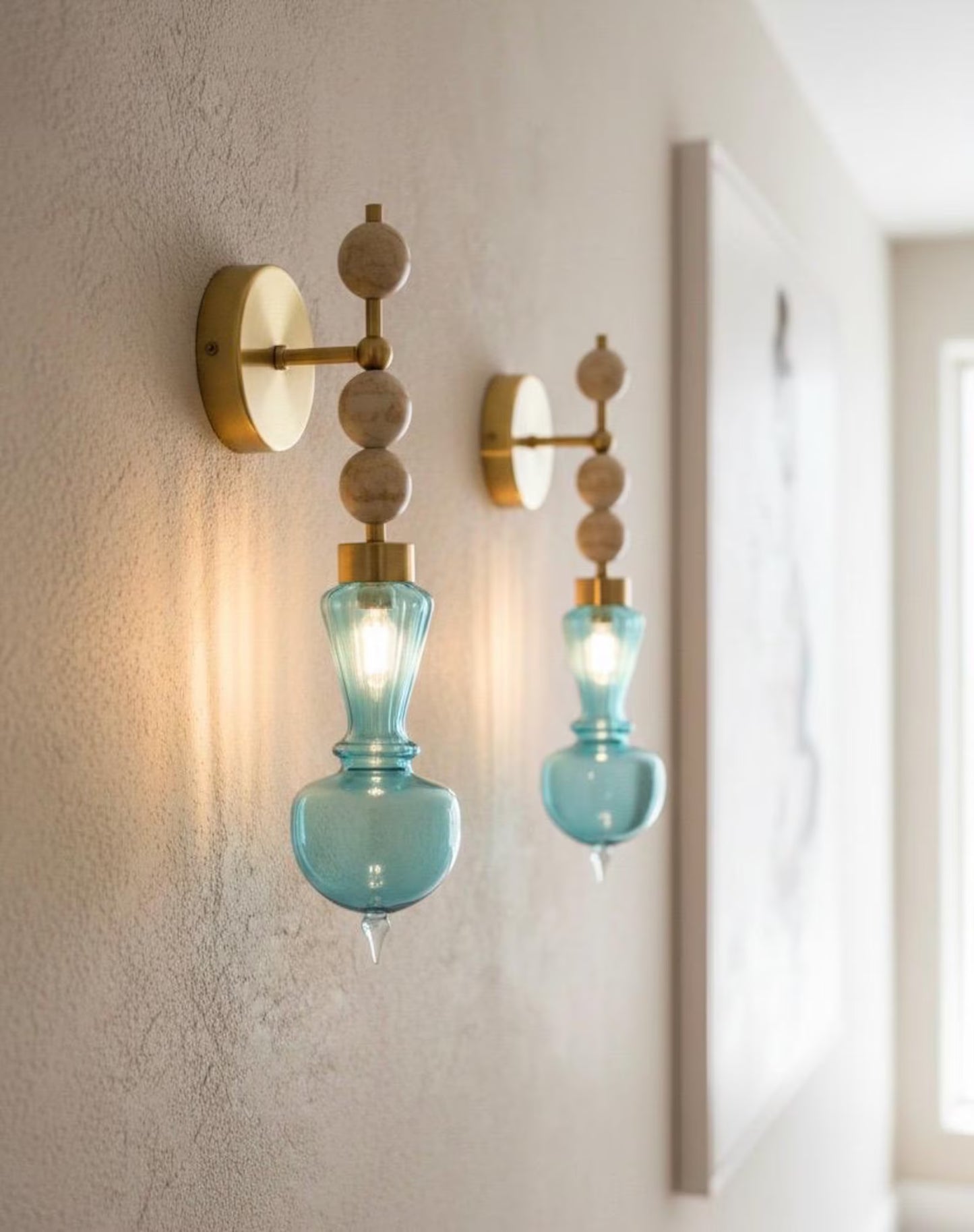 Two wall sconces with blue glass shades on a neutral wall.